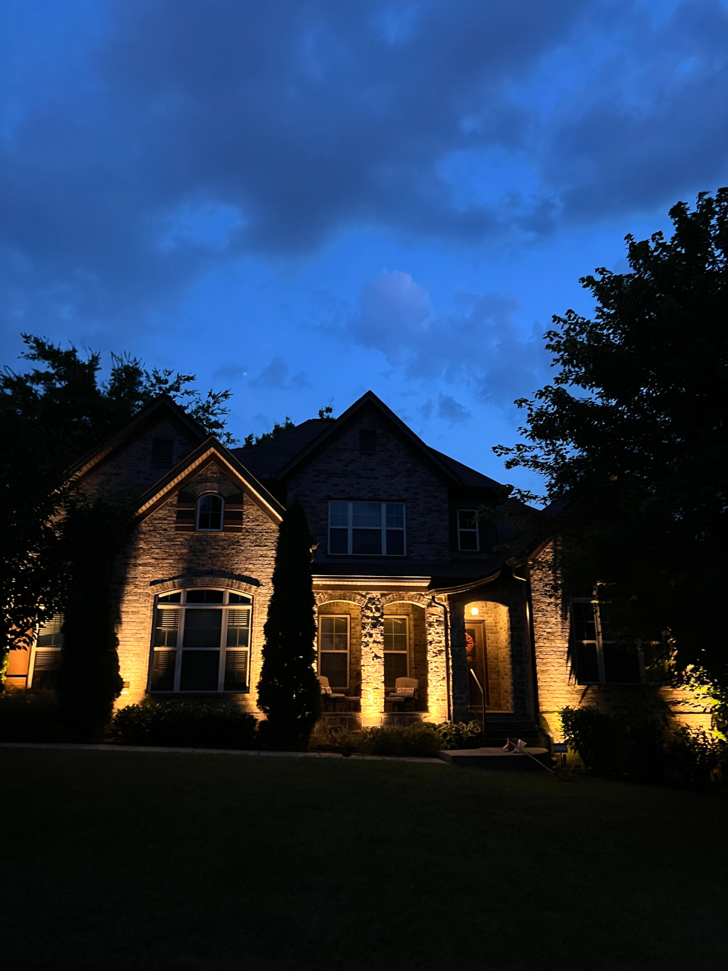 Home exterior with elegant landscape lighting by SGO Land & Tree